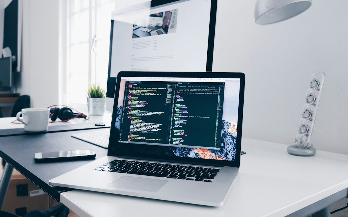 Laptop showing website code beside a desktop website preview